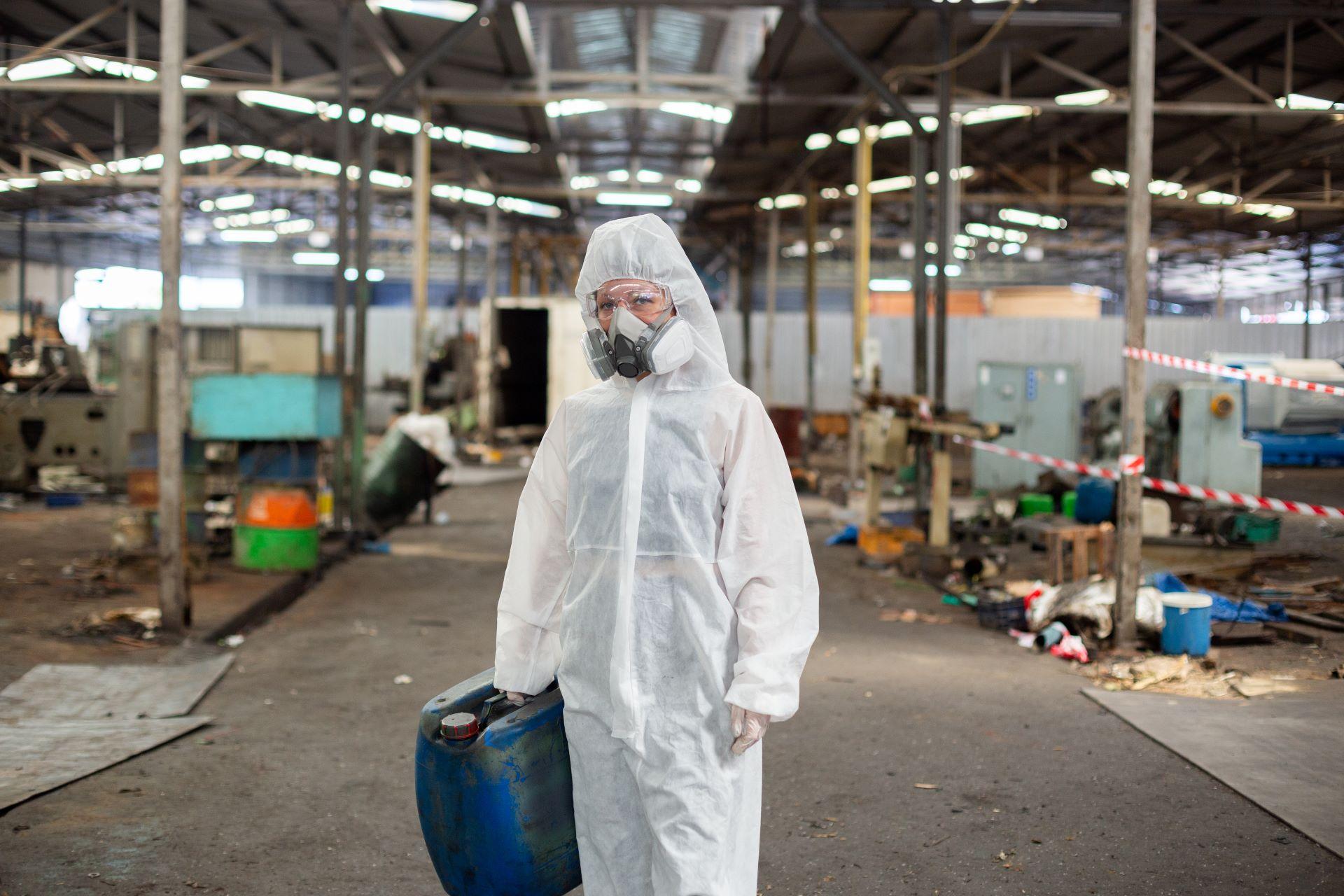 Arbeiter in Schutzanzug und Atemmaske in einer Industriehalle